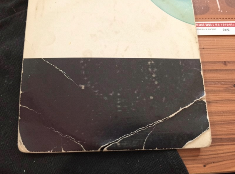 Close-up of a record jacket showing ring wear and a seam split