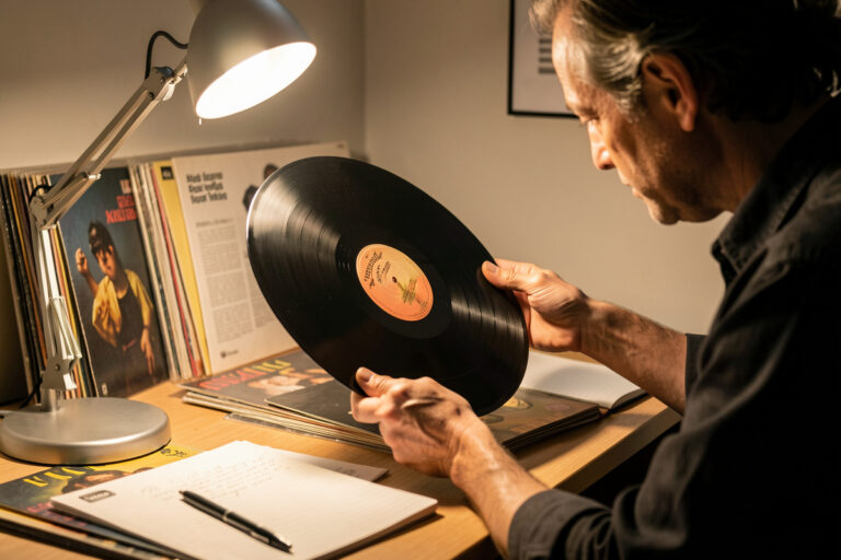 Person grading a vinyl record by holding it up to an angled lamp to inspect the surface