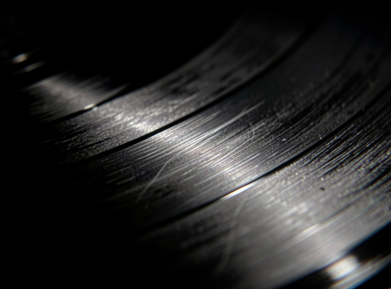 Vinyl record held at a low angle under a single raking lamp to reveal hairlines during visual grading for sale