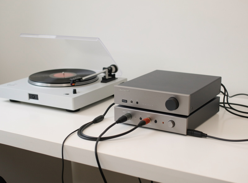 Desktop headphone amplifier and phono stage stacked next to a turntable showing the signal chain