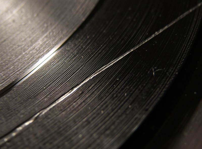 Stylus tracking a record groove with a visible scratch nearby