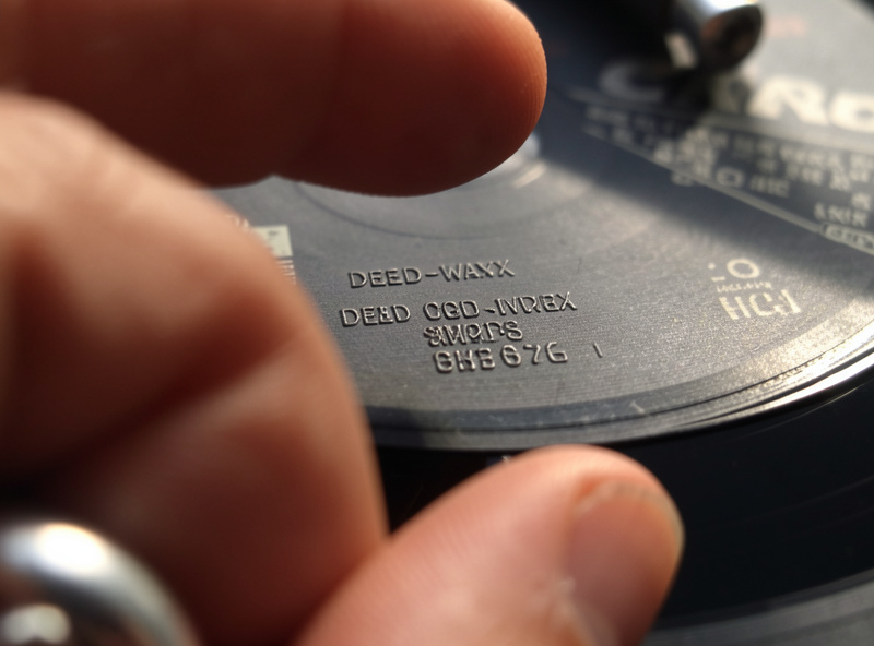 Reading the dead-wax matrix code in a vinyl record run-out groove to match the exact Discogs release for selling