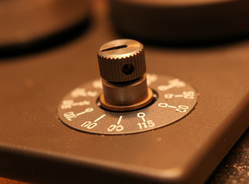 Macro close-up of the anti-skate adjustment dial and weight on a turntable tonearm base
