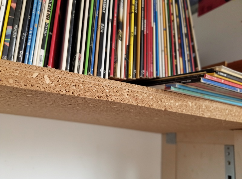 A particleboard shelf bowing under the heavy weight of vinyl records