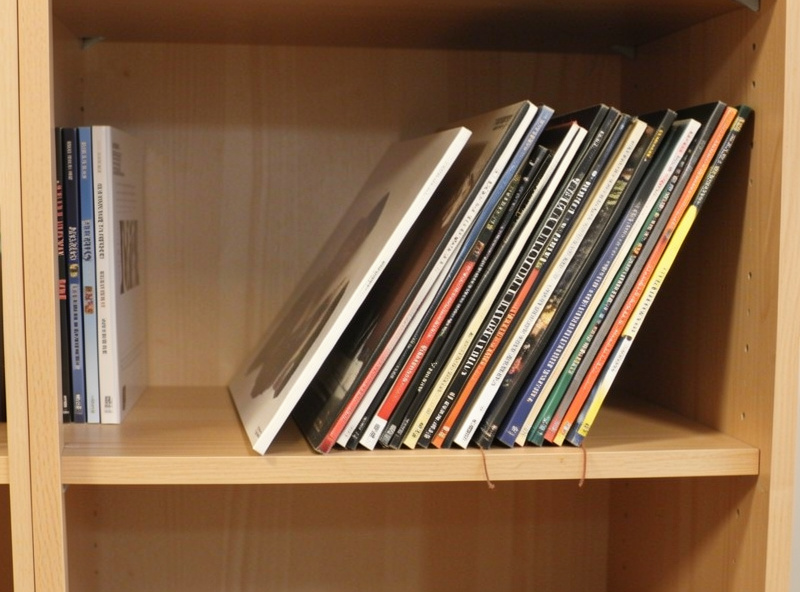 Records leaning at a slant on a half-empty shelf with no end support