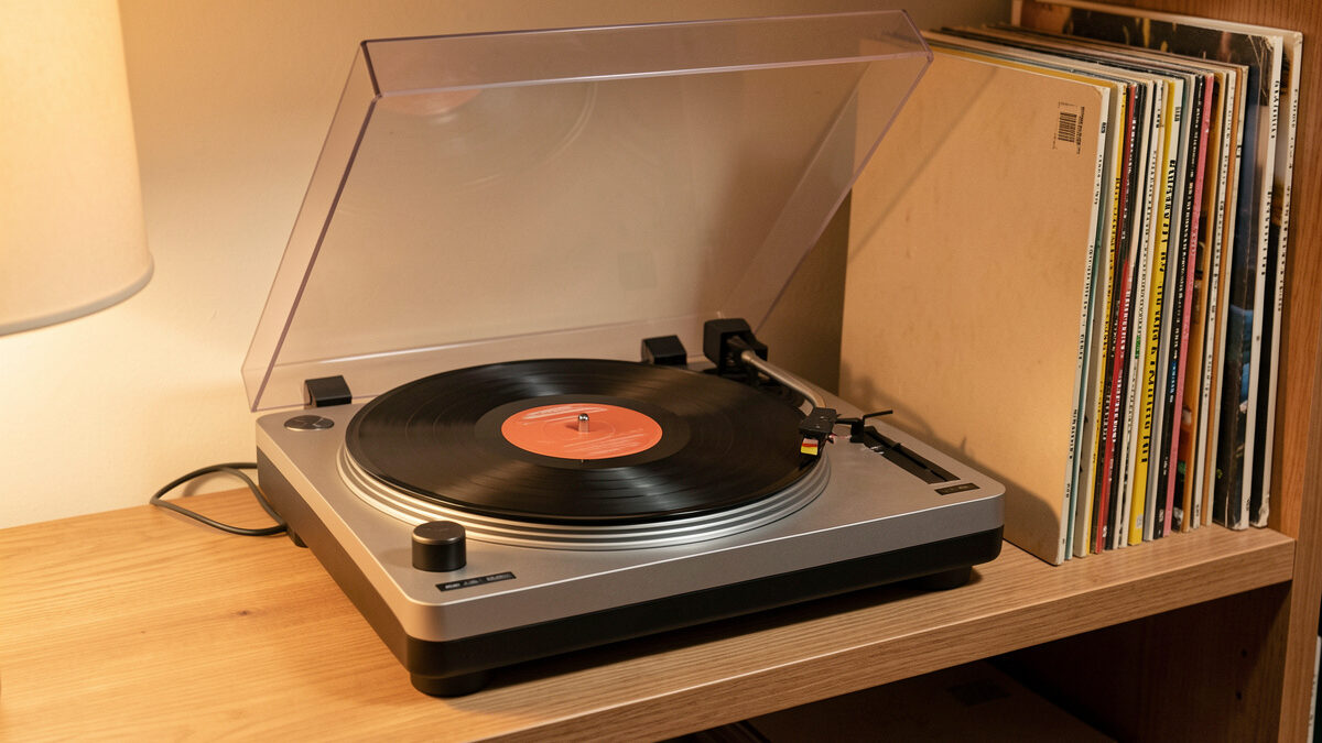 A compact battery-powered turntable playing a record on a wooden shelf with no wires attached