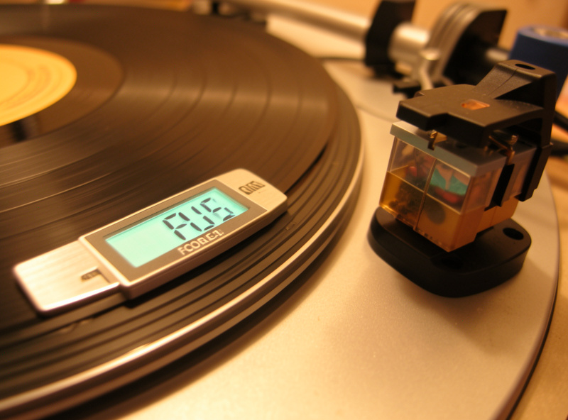 Digital stylus force gauge reading on a turntable platter next to a mounted cartridge