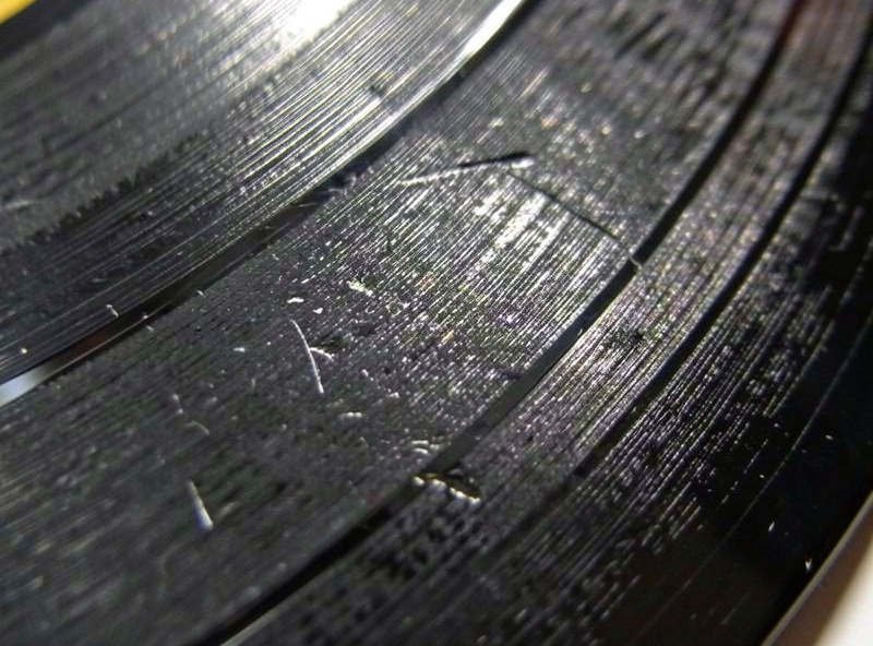 A vinyl record groove under magnification showing the difference between wear and damage