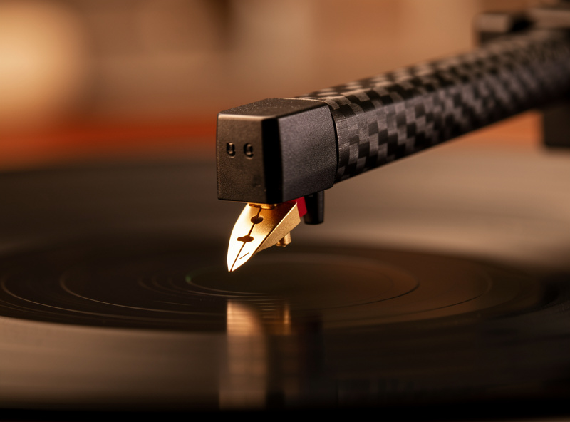 Moving-magnet phono cartridge with a fine elliptical stylus tip mounted on a carbon-fiber tonearm above a record