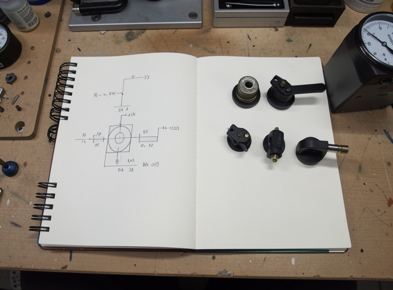Notebook with a resonance calculation sketch beside headshells of different weights and a stylus force gauge