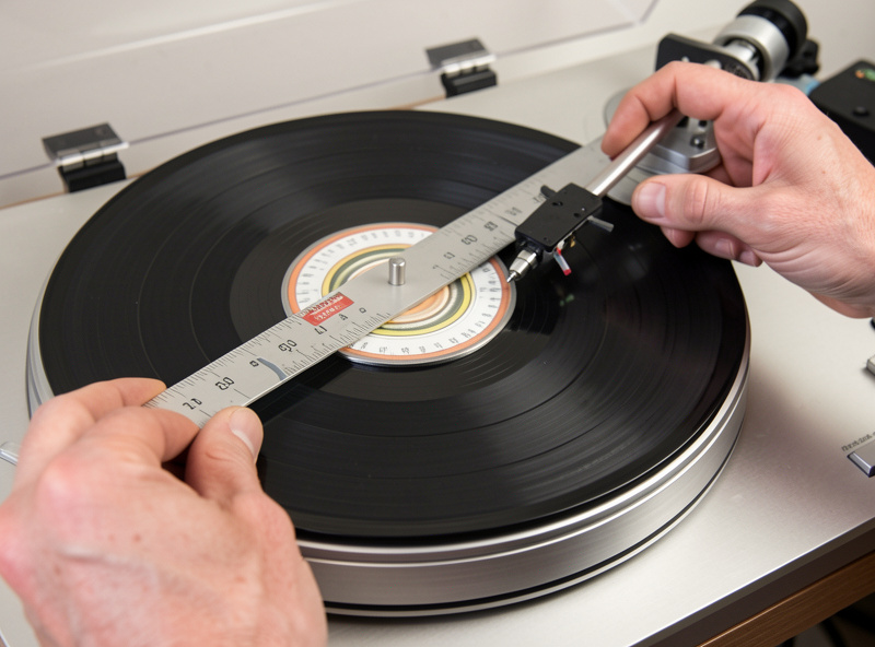 A new turntable being set up with a stylus force gauge and alignment protractor