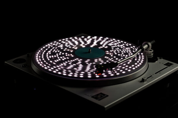 A strobe disc spinning on a portable turntable platter under a strobe light showing speed-check dots