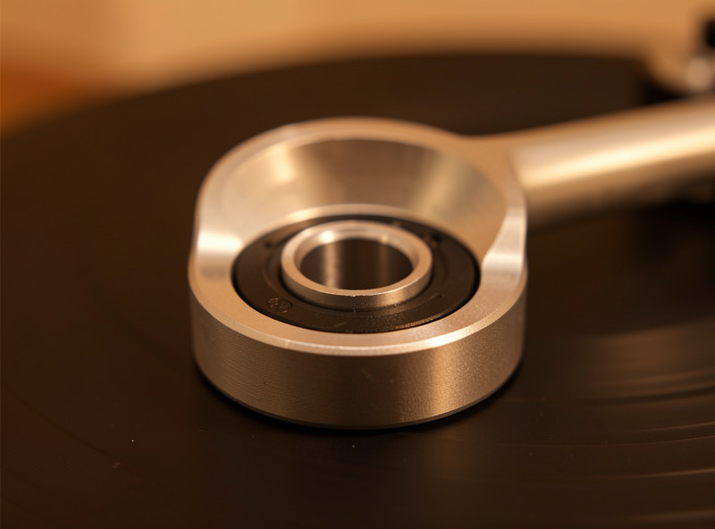 One-piece cast aluminum tonearm bearing housing on a belt-drive turntable, macro detail