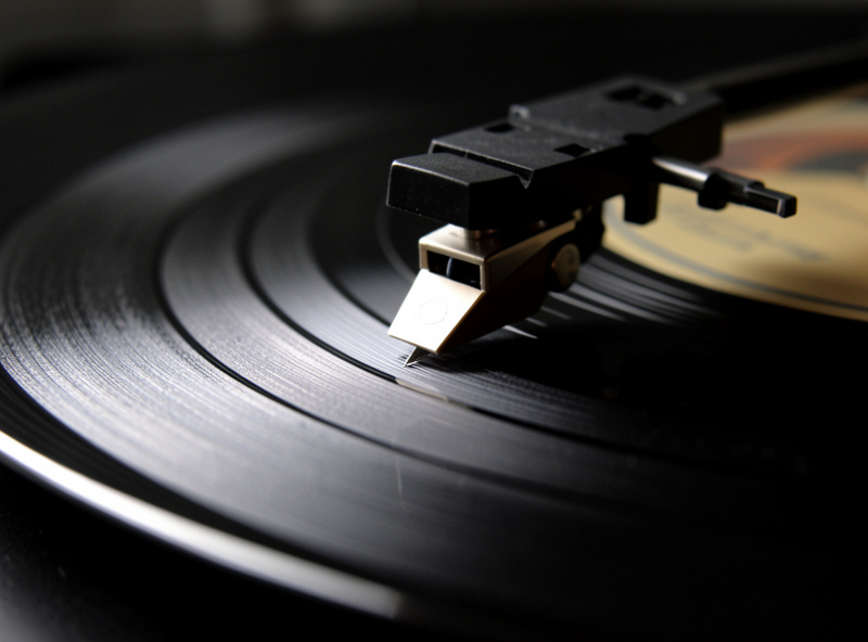 Close-up of a stylus tracking a vinyl record groove under raking light on a turntable platter