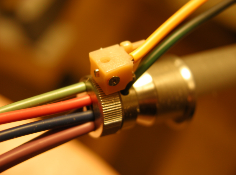 Headshell being mounted onto a tonearm collet with four colored cartridge lead wires visible