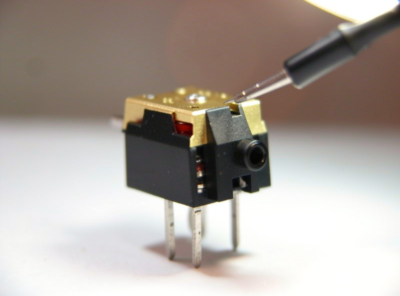 Close-up of a phono cartridge and stylus removed for inspection under bright light
